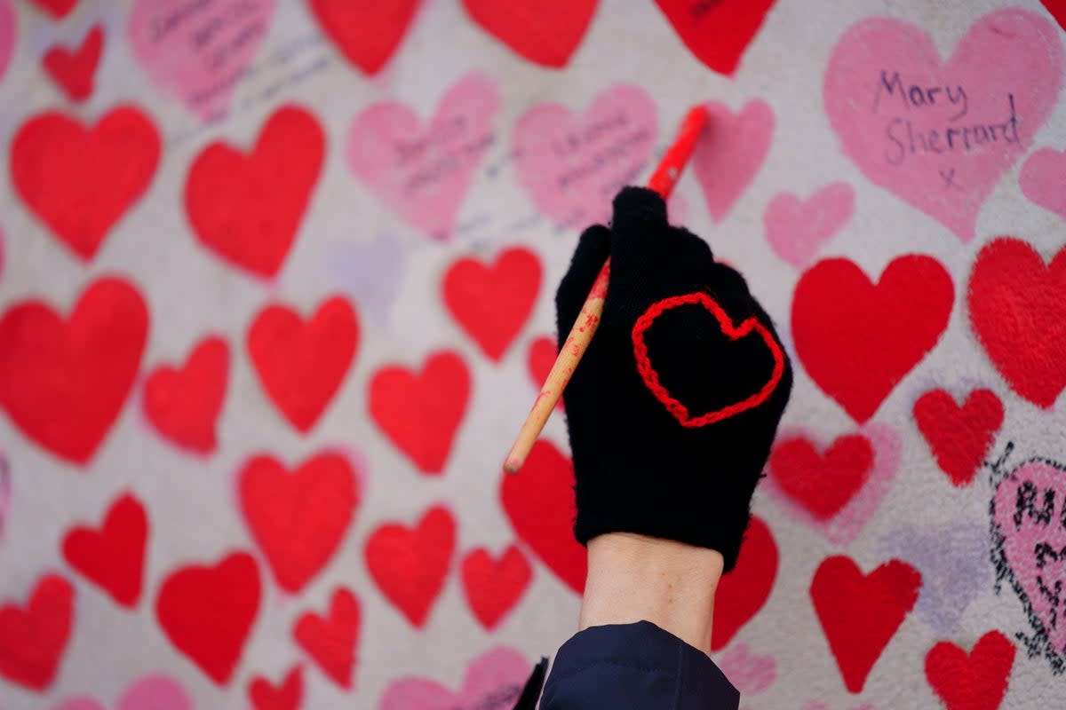 A volunteer from the Covid-19 Bereaved Families for Justice campaign group paints a heart on the National Covid Memorial Wall opposite the Palace of Westminster in central London, which remembers people who have died of the virus. (Victoria Jones/PA) (PA Wire)