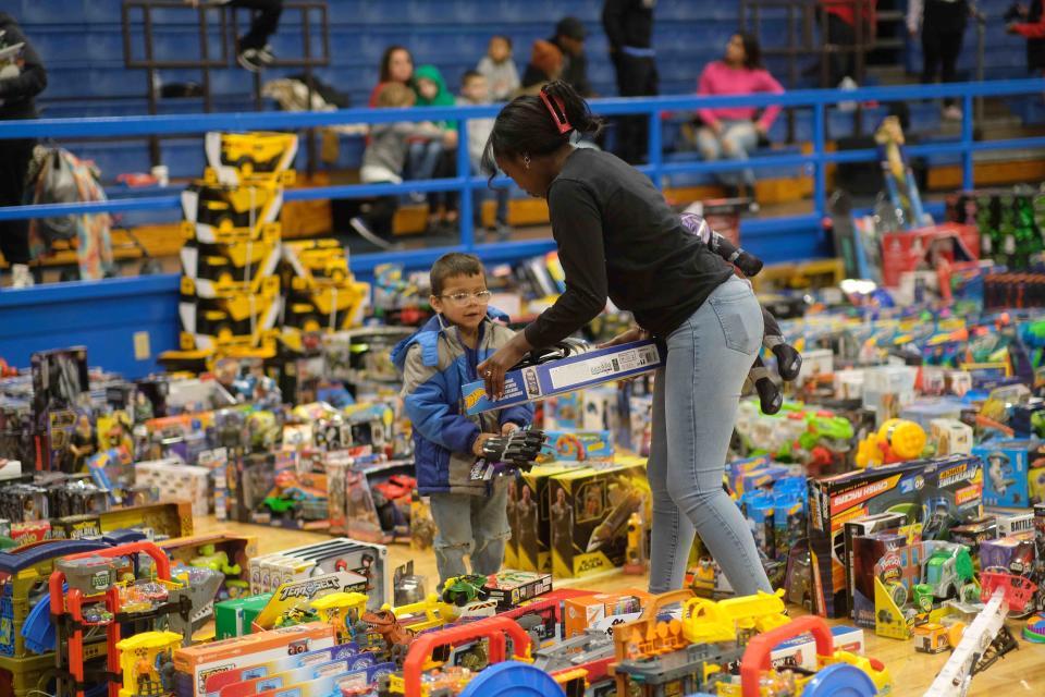 A volunteer helps a child choose a toy Saturday at the 10th annual Northside Toy Drive held at the Palo Duro High School Gym in Amarillo.