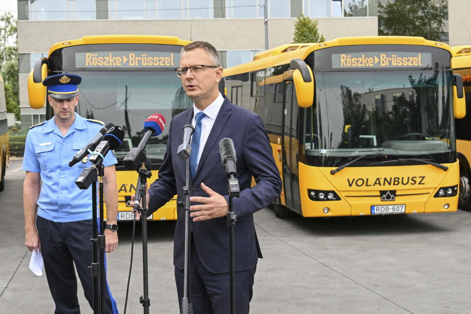 Hungary's State Secretary Bence Rétvári, right, and National Deputy Chief of Police Janos Kuczik hold a joint press conference at the bus station of Nepliget, Budapest, Hungary, Friday Sept. 6, 2024, backdropped by a row of passenger buses with illuminated signs reading “R?szke-Brussels” — a route that would take migrants from Hungary's southern border with Serbia to the EU headquarters in Belgium. (Tibor Illyes/MTI via AP)