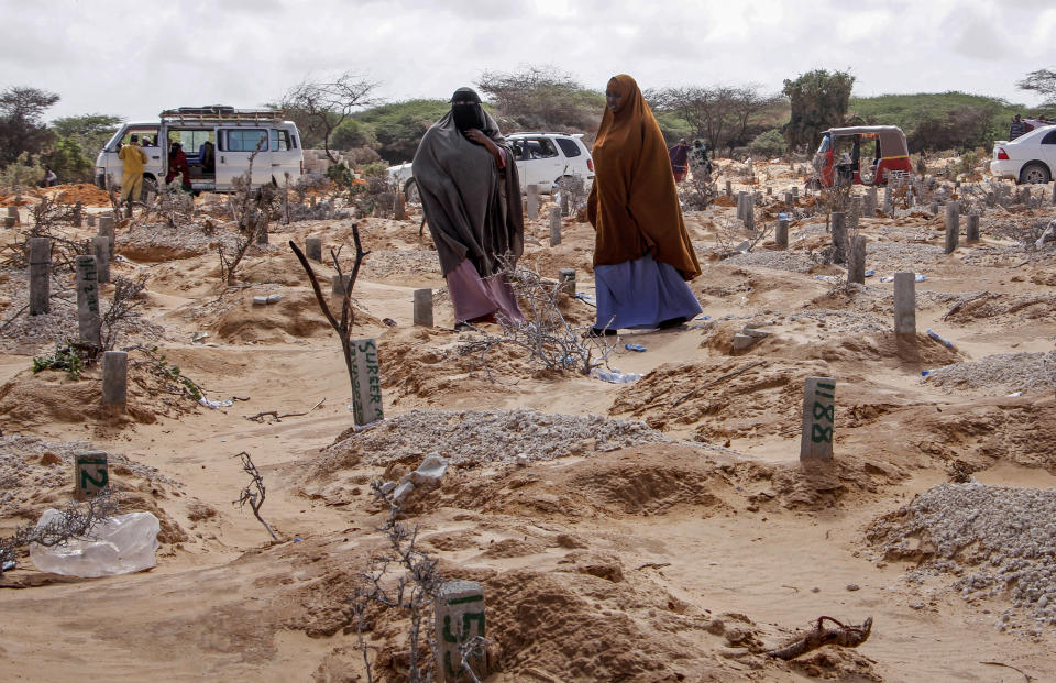 FILE - In this May, 13, 2020, file photo, women walk past graves at a cemetery in Mogadishu, Somalia, following the burial of a man who died of COVID-19. Africa has surpassed 100,000 confirmed deaths from COVID-19 as the continent praised for its early response to the pandemic now struggles with a dangerous resurgence and medical oxygen often runs desperately short. (AP Photo/Farah Abdi Warsameh, File)