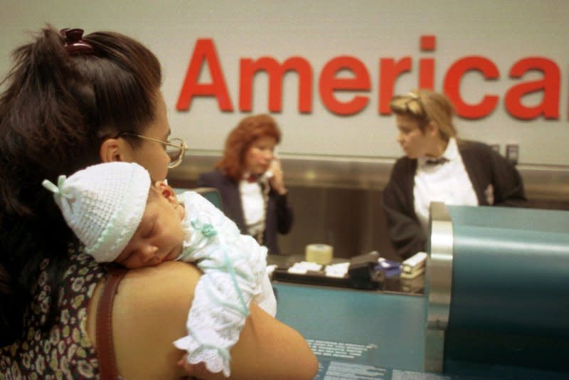 Ileana Lunar, 23 holds her baby Venaz at the American Airlines counter at Miami International Airport on December 21, 1995. Ticket agents were busy dealing with passenger questions regarding American Airlines Flight 965, which crashed in the Andes near Cali, Colombia, on December 20. File Photo by Jeff Widener/UPI