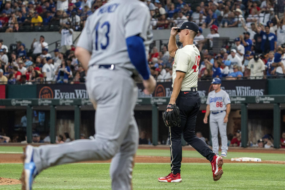 Texas Rangers relief pitcher Glenn Otto, front right, walks back to the mound as Los Angeles Dodgers' Max Muncy (13) rounds the bases on a three-run home run by J.D. Martinez during the fourth inning of a baseball game Saturday, July 22, 2023, in Arlington, Texas. Will Smith also scored on the play. (AP Photo/Jeffrey McWhorter)