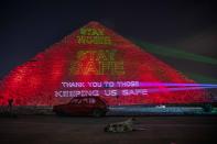 The Ministry of antiquities lights up the pyramids in an expression of support for health workers battling the coronavirus outbreak, Monday, March 30, 2020, in Giza, Egypt. (AP Photo/Nariman El-Mofty)