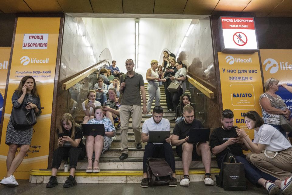 People working on their laptops while they take cover at metro station during a Russian rocket attack in Kyiv, Ukraine, Monday, May 29, 2023. Explosions have rattled Kyiv during daylight as Russian ballistic missiles fell on the Ukrainian capital. The barrage came hours after a more common nighttime attack of the city by drones and cruise missiles. (AP Photo/Evgeniy Maloletka)