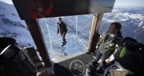 Journalists and employees, wearing slippers to protect the glass floor, stand in the 'Step into the Void' installation during a press visit at the Aiguille du Midi mountain peak above Chamonix, in the French Alps, December 17, 2013. The Chamonix Skywalk is a five-sided glass structure installed on the top terrace of the Aiguille du Midi (3842m), with a 1,000 metre drop below, where visitors can step out from the terrace, giving the visitors the impression of standing in the void. The glass room will open to the public on December 21, 2013. REUTERS/Robert Pratta (FRANCE - Tags: SOCIETY TRAVEL CITYSCAPE)