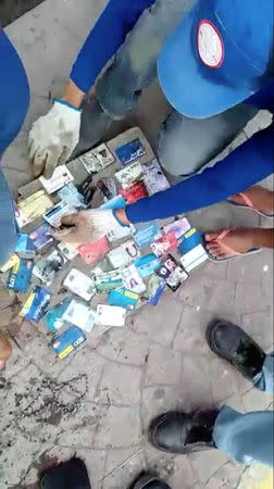 Sanitation workers sort out credit cards and IDs after retrieving wallets from a drain, after local media reported that a stash of wallets were clogging a canal in Poblacion, Batangas City, Philippines October 16, 2018, in this still image taken from a video obtained from social media. Domav Panganiban/via REUTERS