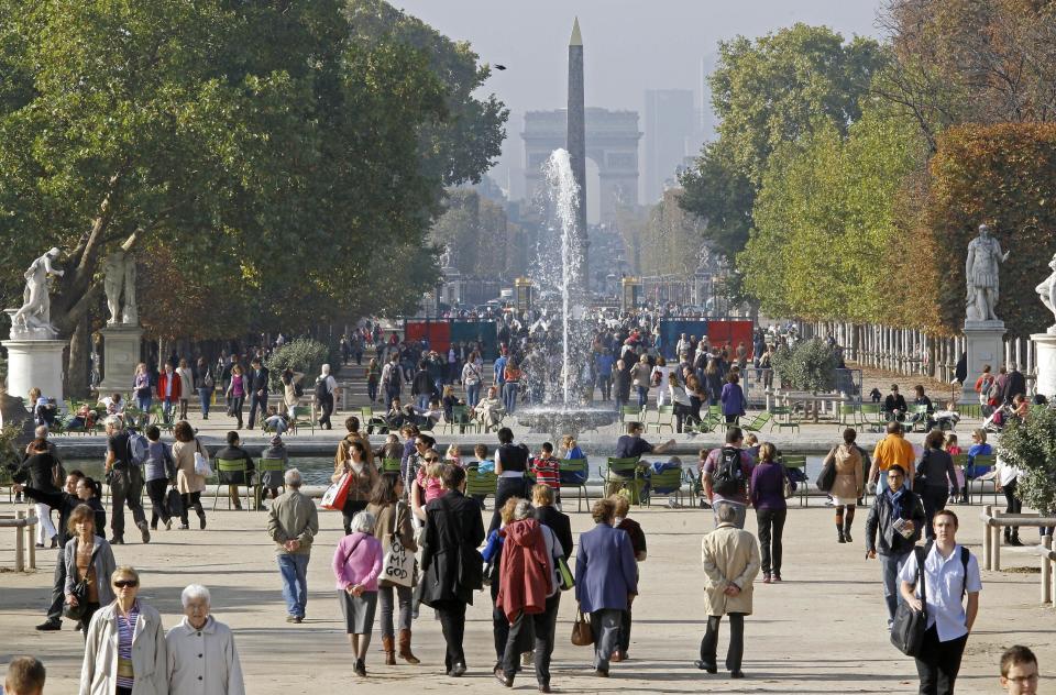 This Oct. 23, 2012 photo shows people strolling in the Tuileries gardens, with the Arc de Triomphe in background, in Paris. The 400-year-old Tuileries gardens sitting tranquilly in the heart of the capital between the Louvre Museum and the Place de la Concorde offers a place to relax with their ornate fountains, magical statues and fresh air. (AP Photo/Remy de la Mauviniere)