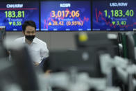 A currency trader passes by screens showing the Korea Composite Stock Price Index (KOSPI), center, and the foreign exchange rate between U.S. dollar and South Korean won, right, at the foreign exchange dealing room of the KEB Hana Bank headquarters in Seoul, South Korea, Friday, Oct. 15, 2021. Asian shares were higher Friday after technology companies powered the biggest gain on Wall Street since March. (AP Photo/Ahn Young-joon)