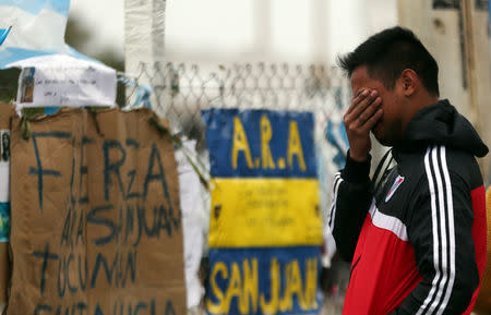 A man reacts in front of signs and messages in support of the 44 crew members of the missing at sea ARA San Juan submarine on a fence at an Argentine naval base in Mar del Plata, Argentina November 23, 2017. REUTERS/Marcos Brindicci