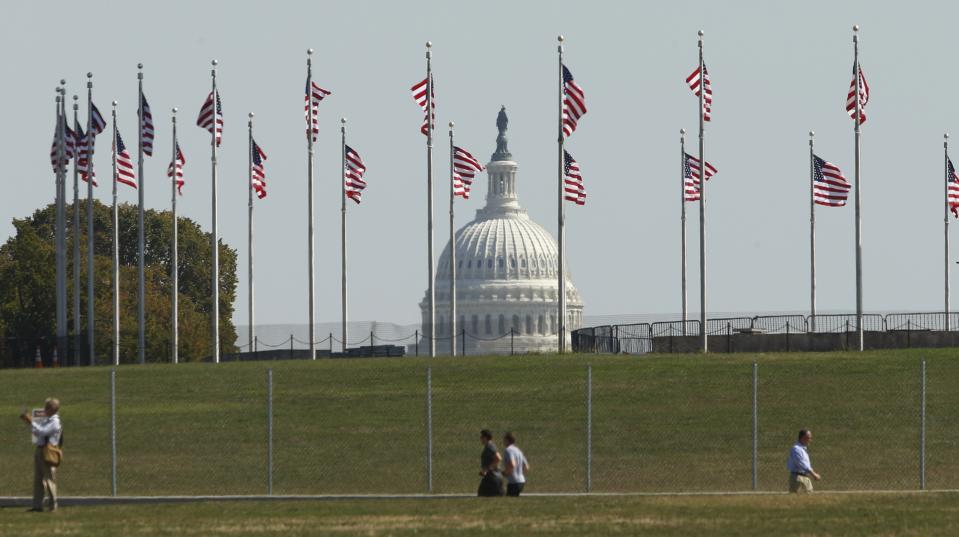 The dome of the U.S. Capitol is seen though American Flags in Washington October 1, 2013. Up to one million federal workers were thrown temporarily out of work on Tuesday as the U.S. government partially shut down for the first time in 17 years in a standoff between President Barack Obama and congressional Republicans over healthcare reforms. REUTERS/Kevin Lamarque (UNITED STATES - Tags: POLITICS BUSINESS)