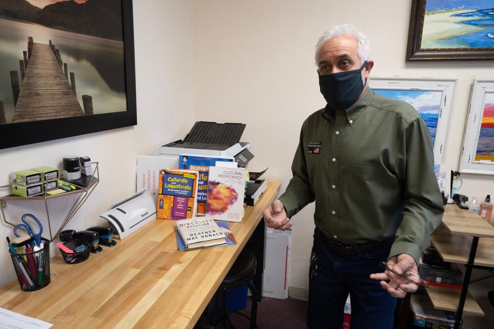 Rick Reynaud, a member of Coalition of Conservatives in Action, stands in his office by a collection of books that he believes should be eliminated from school curricula.