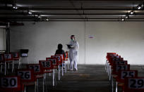 A nurse in protective clothing takes notes from a woman with symptoms of new coronavirus at a carpark that turned into a COVID-19 infection screening center at Chulalongkorn University health service center in Bangkok, Thailand, Wednesday, April 1, 2020. The new coronavirus causes mild or moderate symptoms for most people, but for some, especially older adults and people with existing health problems, it can cause more severe illness or death. (AP Photo/Gemunu Amarasinghe)