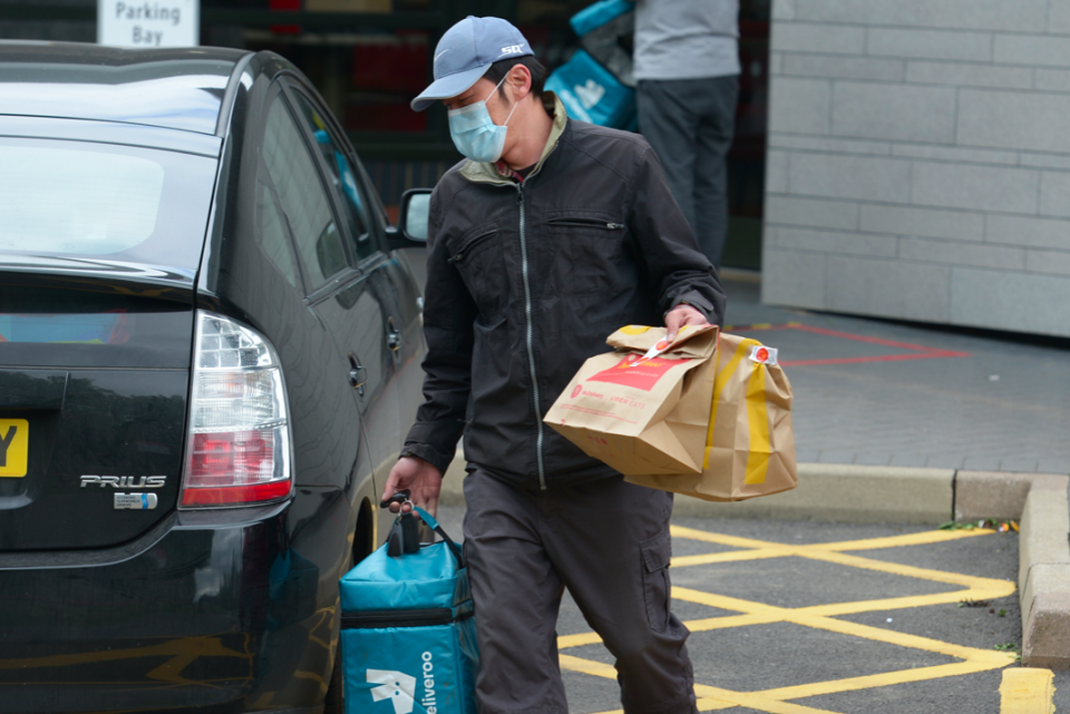 A delivery driver takes bags of McDonald's out to customers in Chelmsford, Essex. (PA)