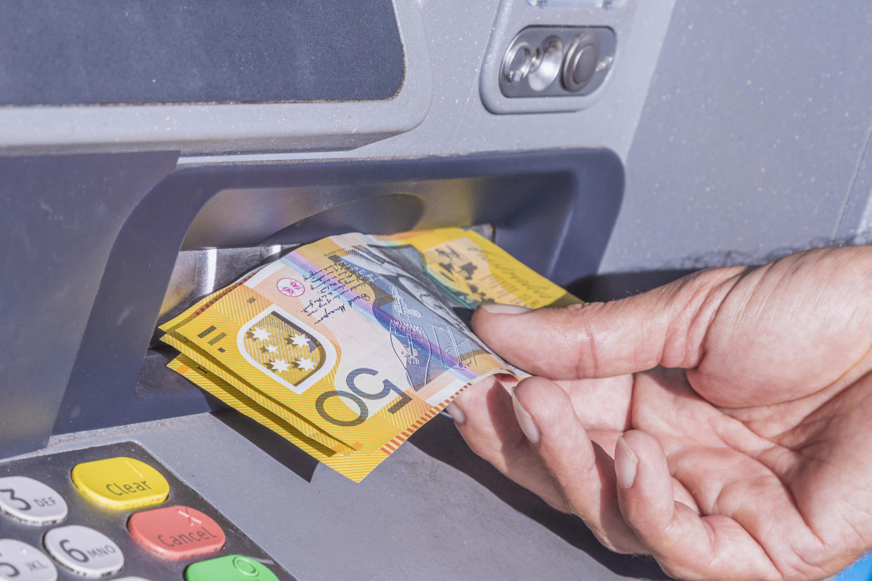 Taking several Australian $50 notes from an ATM machine