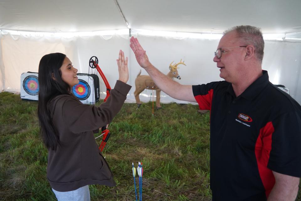 Sixth-grader Isabel Jop of Milwaukee gets a high five from archery instructor Scott Cleland of Kenosha at the Midwest Outdoor Heritage Education Expo. The event was held May 10 at Havenwoods State Forest in Milwaukee. It was Jop's first time shooting a bow and arrow.