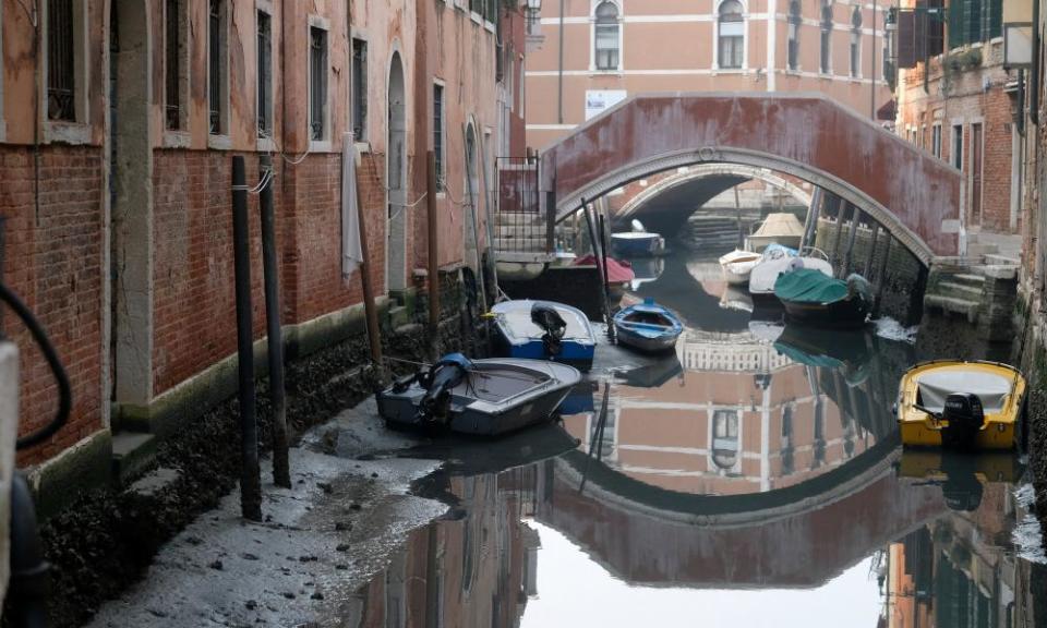 Boats in a Venice canal during a severe low tide in the lagoon city.