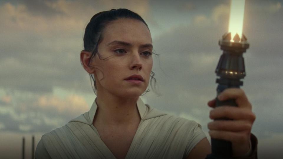 Daisy Ridley looks at her yellow lightsaber in The Rise of Skywalker