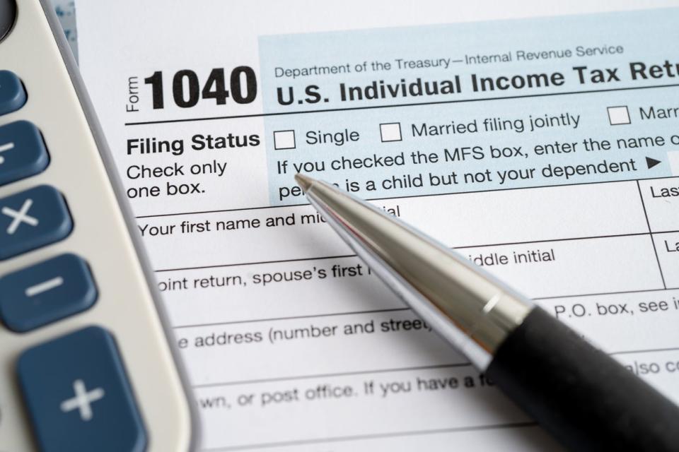 A 1040 tax form with calculator and pen.