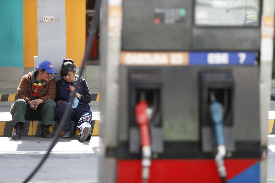 Workers sit at a gas station in La Paz, Bolivia, Thursday, Nov. 14, 2019. Gas stations have run out of fuel as the result of followers of former President Evo Morales blocking the main highway. (AP Photo/Natacha Pisarenko)