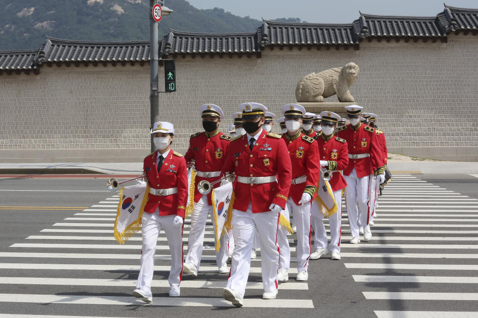 Members of the South Korean military band wearing face masks to help protect against the spread of the new coronavirus cross a road during an event to commemorate the upcoming 70th anniversary of the Korean War, in Seoul, South Korea, Monday, June 15, 2020. (AP Photo/Ahn Young-joon)