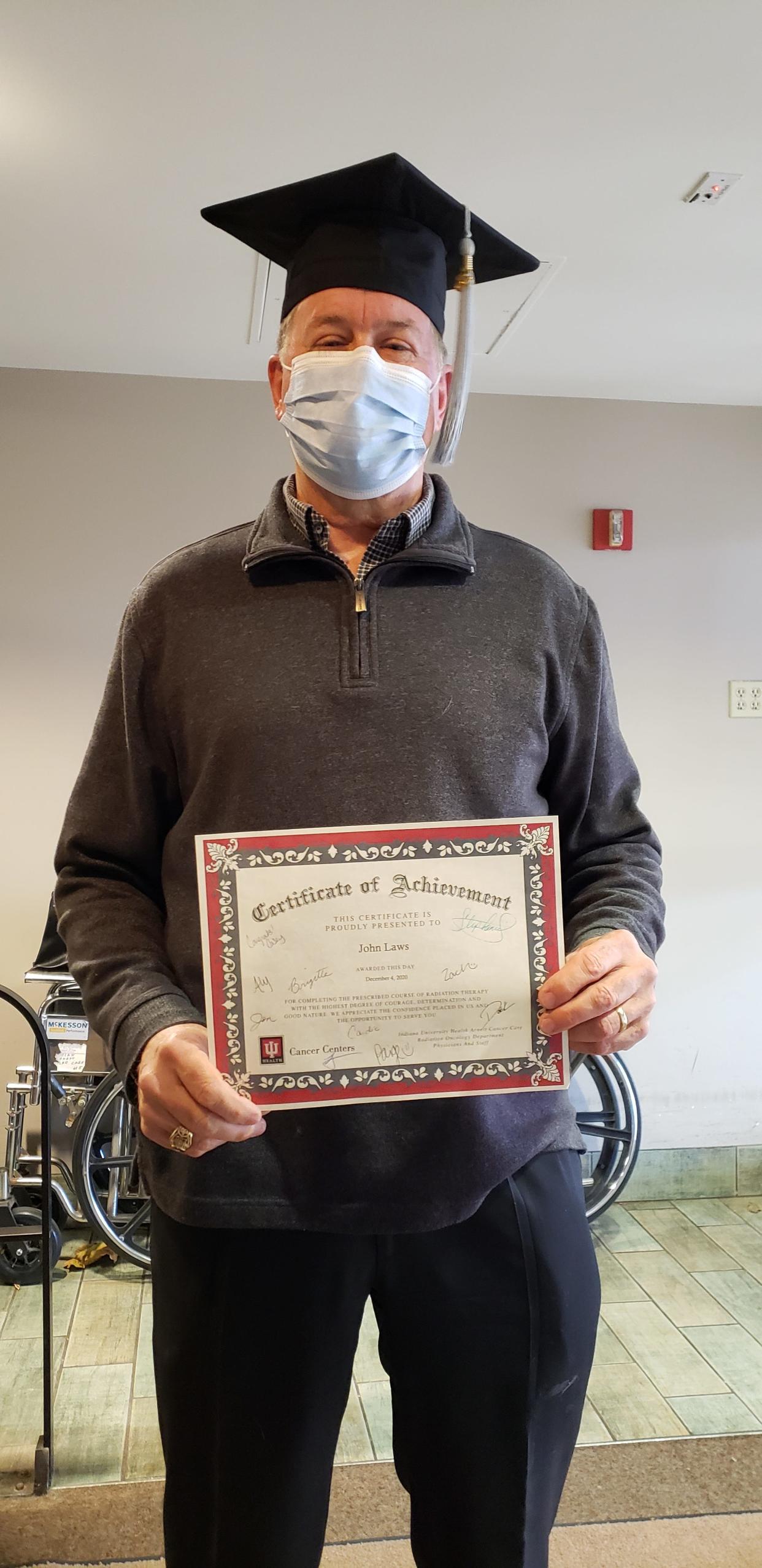 John Laws holds his certificate of achievement after completing his prescribed round of radiation treatment. Laws recently donated a blanket warmer for other patients at IU Health Arnett to use.