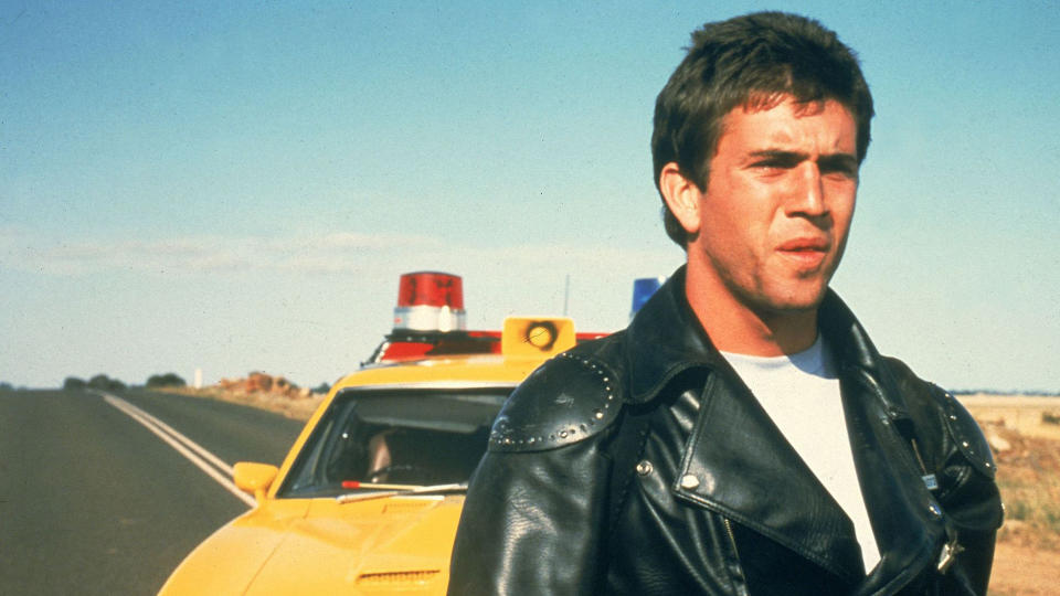 A close up of Max Rockatansky standing in front of his yellow cop car in 1979's Mad Max film