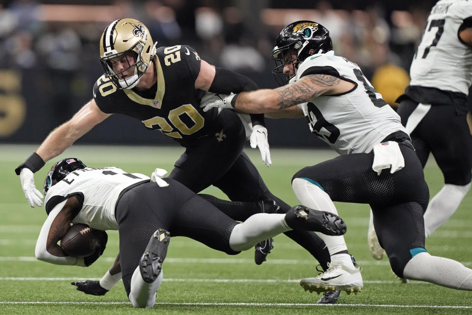 Jacksonville Jaguars running back Travis Etienne Jr., left, dives for extra yardage against New Orleans Saints linebacker Pete Werner (20) in the first half of an NFL football game in New Orleans, Thursday, Oct. 19, 2023. (AP Photo/Gerald Herbert)