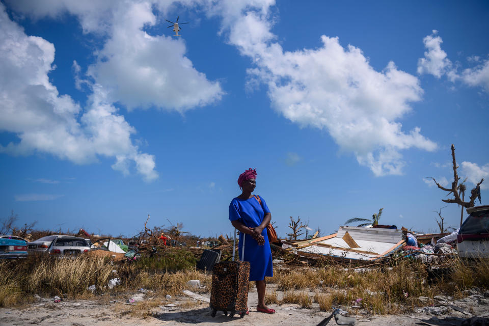 Dejani Louistan, who was displaced by Hurricane Dorian, stands with the only belongings she managed to salvage amid the destruction left in the Mudd neighborhood of Marsh Harbour, Bahamas on September 7, 2019. | Carolyn Van Houten—The Washington Post via Getty Images