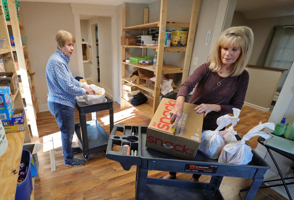 Copley Outreach Center volunteers Carla Ringer, left, and Diane DeBart prepare food bags for Copley-Fairlawn school district students.