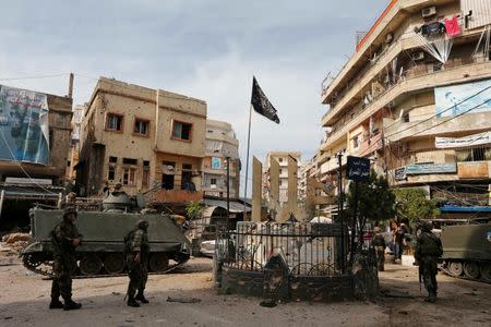 Lebanese army soldiers stand near damaged buildings after being deployed to tighten security, following clashes between Lebanese soldiers and Islamist gunmen in Tripoli, northern Lebanon October 27, 2014. REUTERS/Mohamed Azakir