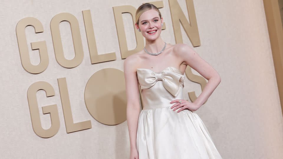 Elle Fanning went for a simple cream vintage Pierre Balmain with an oversized bow bodice detail, Cartier jewels and sleek updo. - John Salangsang/Golden Globes/Getty Images