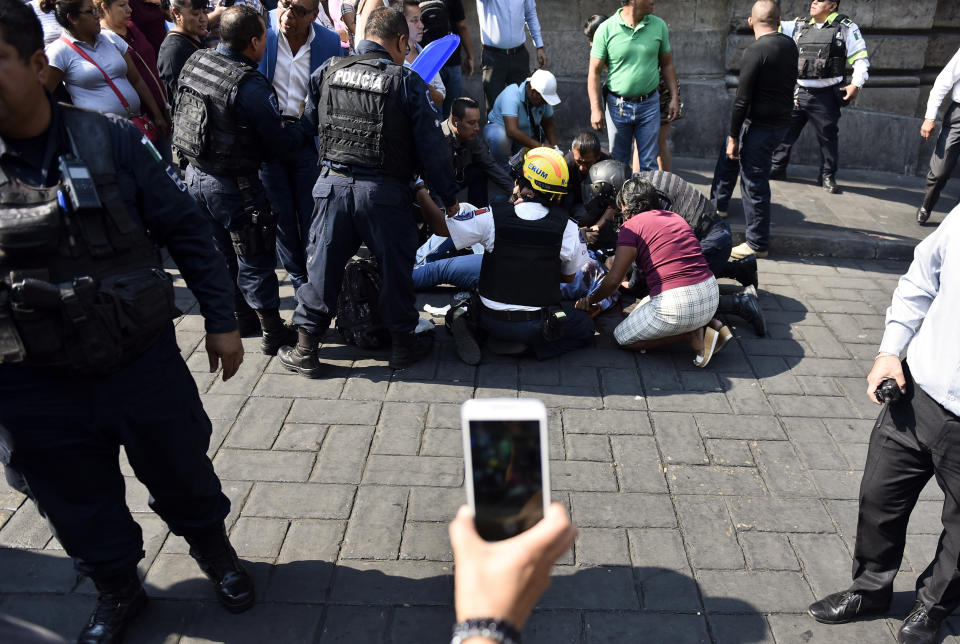 Police and paramedics attend a person who was wounded by a shooter outside City Hall in Cuernavaca, Mexico, Wednesday, May 8, 2019. A man opened fire at the entrance of City Hall where journalists were interviewing government officials, killing two people, including a union member who was apparently with street vendors who were protesting nearby, and injuring two others, including a TV cameraman, according to officials. (AP Photo/Tony Rivera)