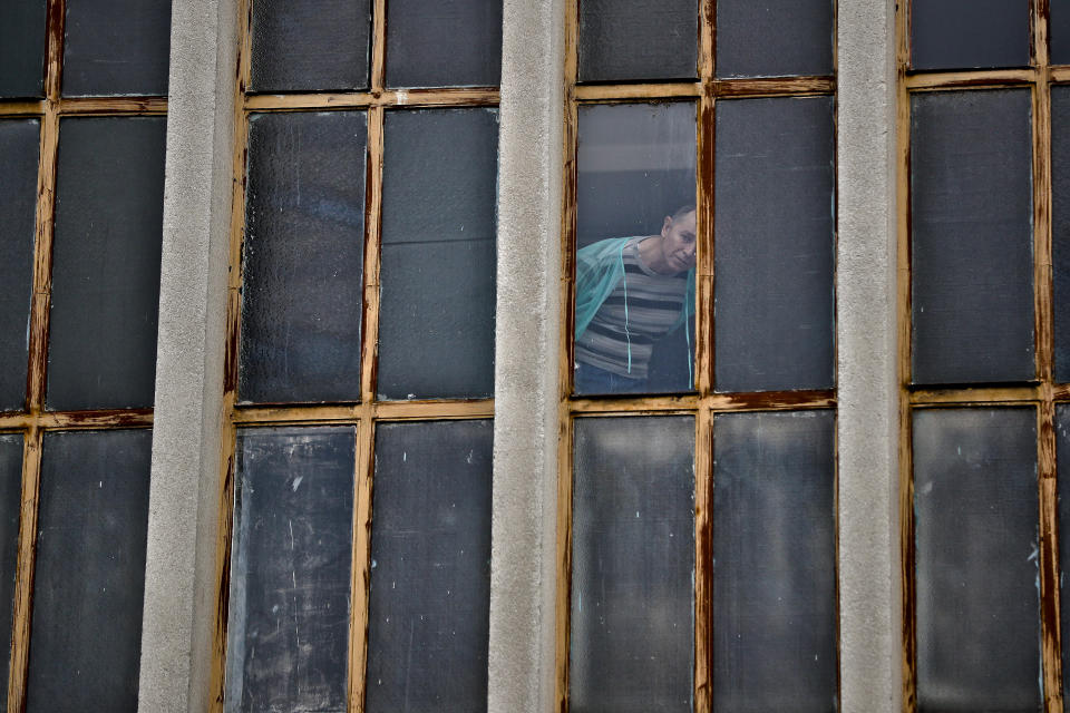 FILE - In this Sunday, Oct. 30, 2016, file photograph a man watches from a hospital a silent march in memory of those who died a year ago at the Colectiv nightclub in Bucharest, Romania. The Oscar-nominated Romanian documentary film “Collective” follows a group of journalists delving into the state of health care in the eastern European country in the wake of a deadly 2015 nightclub fire that left dozens of burned victims in need of complex treatment. What they revealed was decades of deep-rooted corruption, a heavily politicized system scarily lacking in care. (AP Photo/Vadim Ghirda, File)