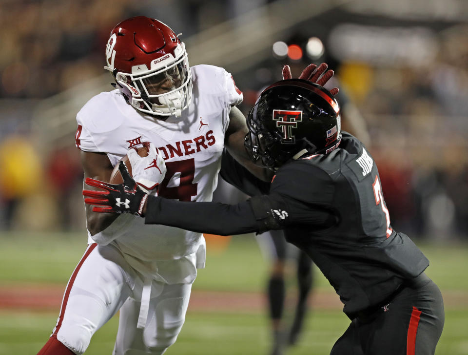 Oklahoma's Trey Sermon (4) tries to break away from Texas Tech's Jah'Shawn Johnson (7) during the first half of an NCAA college football game Saturday, Nov. 3, 2018, in Lubbock, Texas. (AP Photo/Brad Tollefson)