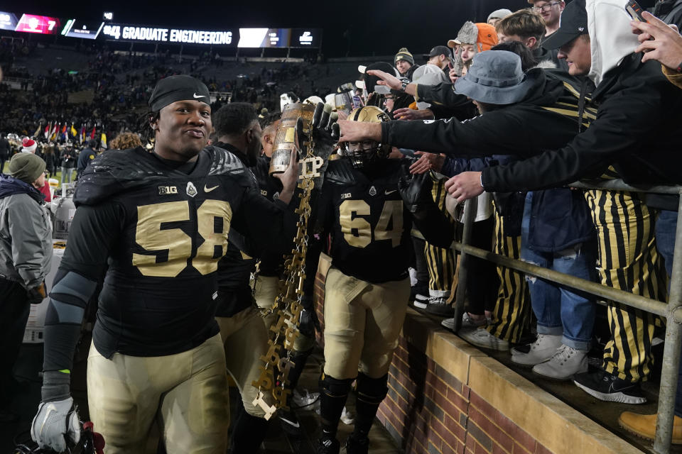 Purdue's Branson Deen (58), Jaylan Alexander and Mahamane Moussa (64) carry the Old Oaken Bucket after Purdue defeated Indiana 44-7 in an NCAA college football game, Saturday, Nov. 27, 2021, in West Lafayette, Ind.(AP Photo/Darron Cummings