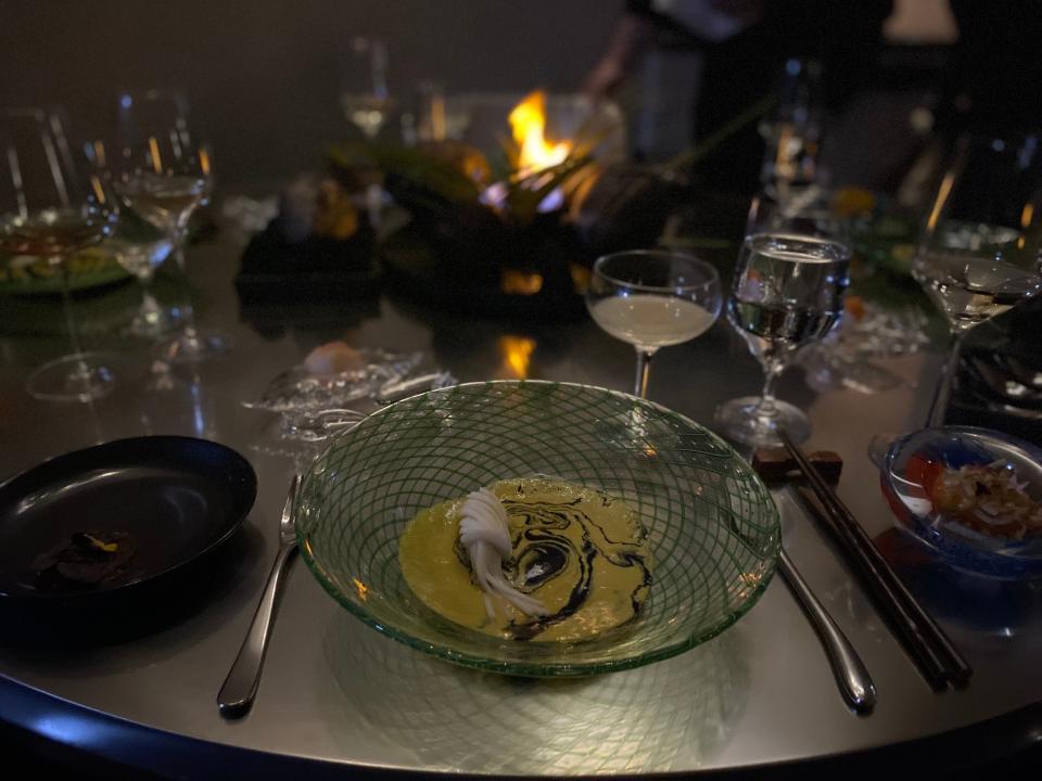 a glass bowl with yellow stuff inside at a dimly lit metal table