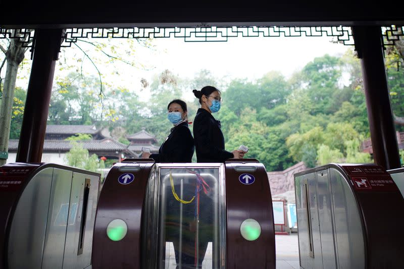 Staff members wearing face masks hold thermometers at an entrance to the Yellow Crane Tower attraction in Wuhan