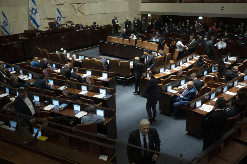 Israeli lawmaker Yair Lapid, foreground, walks the floor of Israel's parliament, the Knesset, as lawmakers convene for a vote on a contentious plan to overhaul the country's legal system, in Jerusalem, Monday, Feb. 20, 2023. (AP Photo/Maya Alleruzzo, Pool)