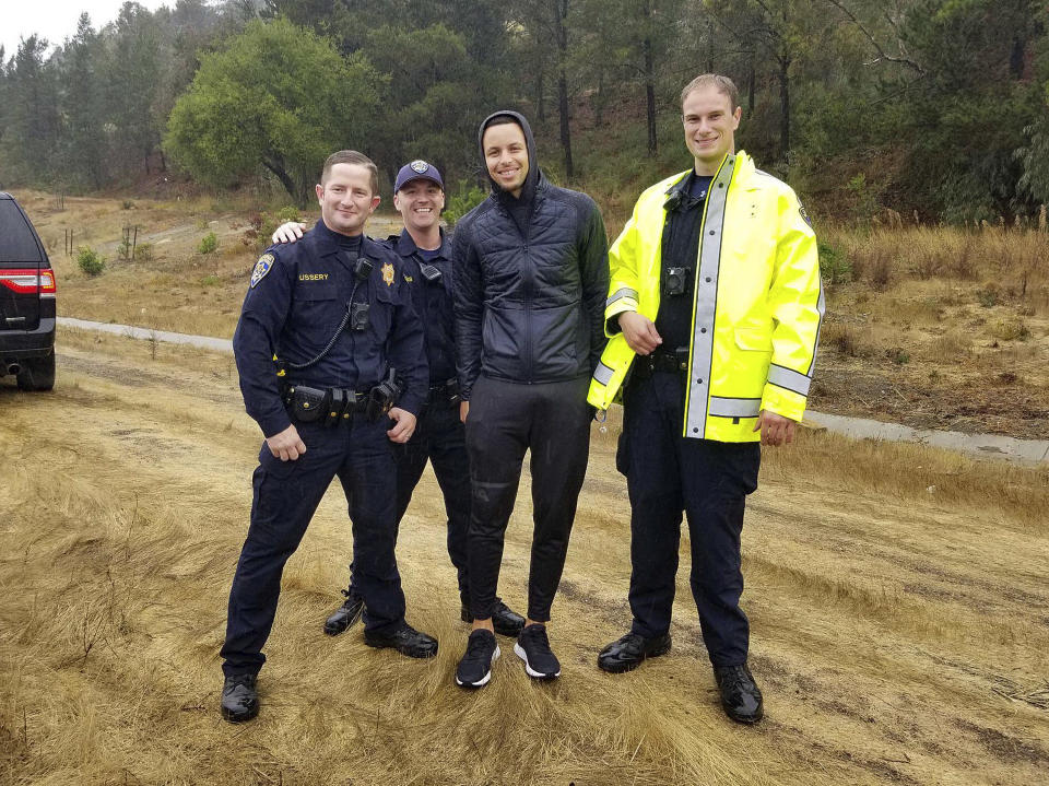 This photo provided by the California Highway Patrol, Oakland Division, NBA Golden State Warriors basketball star Stephen Curry, second from right, poses with CHP Officers, from left, Ussery, Childress and Anderson, after two drivers hit Curry's car on an Oakland, Calif., freeway Friday morning, Nov. 23, 2018. Authorities say that, first, the driver of a Lexus lost control and struck Curry's car. After Curry stopped in the center median and waited for officers to arrive, another sedan lost control and rear-ended his Porsche. No one was injured or arrested and the CHP says that rain was a factor in the crash. (California Highway Patrol Oakland via AP)