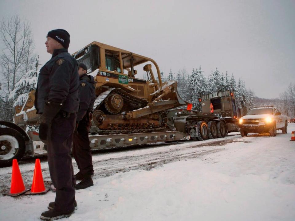 RCMP officers look on as contractors pass through their roadblock, as supporters of the Unist'ot'en camp and Wet'suwet'en First Nation gather at a camp fire off a logging road near Houston, B.C., on Wednesday, Jan. 9, 2019. (Chad Hipolito/THE CANADIAN PRESS - image credit)