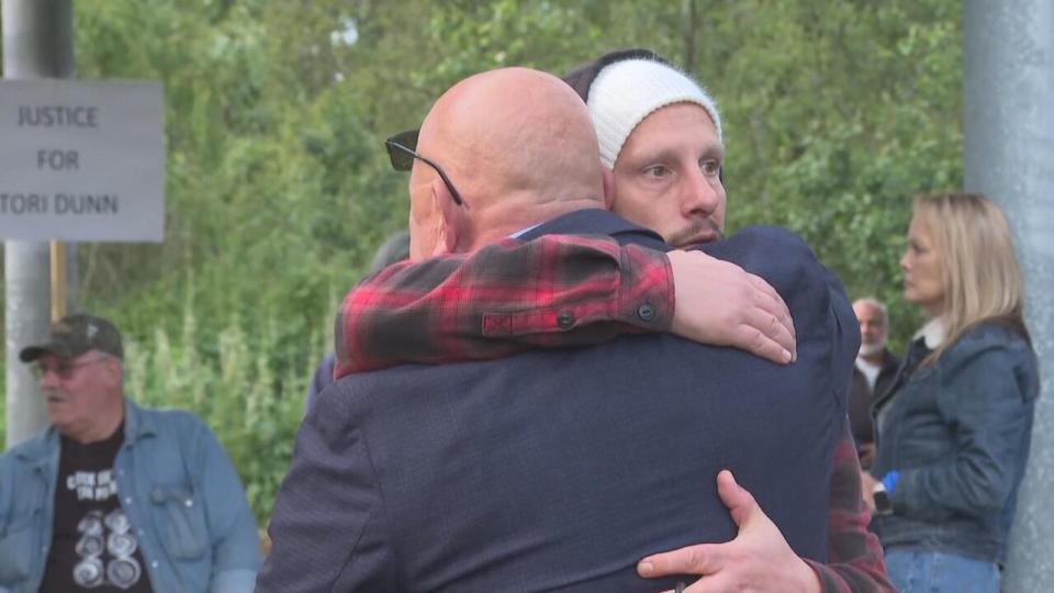 Aron Dunn, the father of slain Surrey woman Tori Dunn, hugs another person with his back to the camera. Aron says his daughter died in a home invasion, and police have not given the family details.