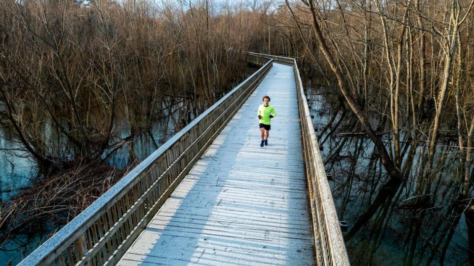 Zachary Bugg runs along Crabtree Creek Trail in Raleigh after a light dusting of snow accumulated on the boardwalk structures on the trail Saturday morning, Jan. 29, 2022.