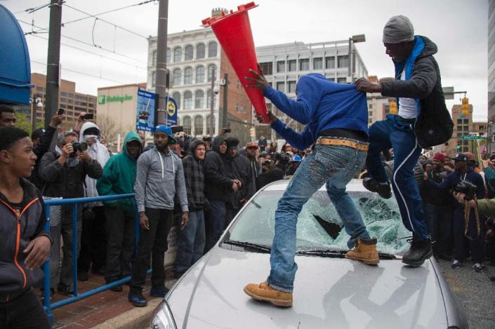 Demonstrators destroy the windshield of a Baltimore Police car on April 25, 2015 as they protest the death of Freddie Gray, an African American man who died of spinal cord injuries while in police custody (AFP Photo/Jim Watson)