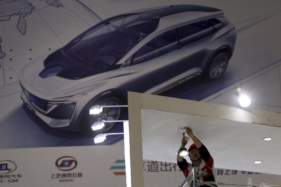 In this April 15, 2019, photo, an electrician installs lights at the Auto Shanghai 2019 show in Shanghai. China's electric car sales are stalling following the end of multibillion-dollar subsidies that made it the biggest market for the technology. Communist leaders want to make China a leader in electric cars but are shifting the burden to the industry by imposing mandatory sales quotas. (AP Photo/Ng Han Guan)