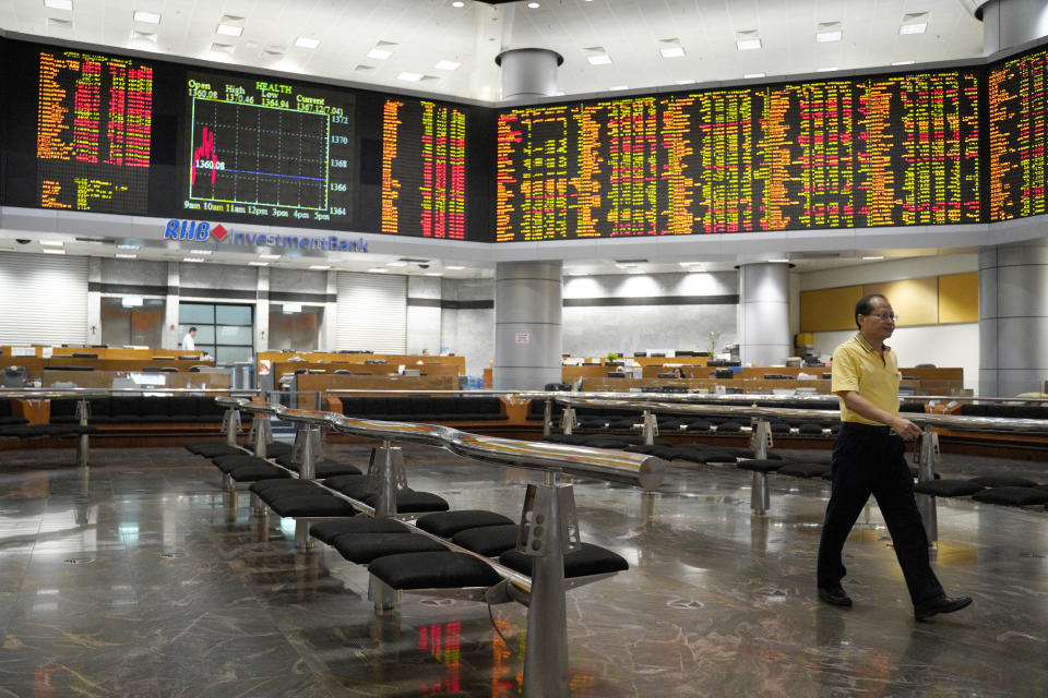 An Investor walks in front of stock trading boards at a private stock market gallery in Kuala Lumpur, Malaysia, Friday, Nov. 30, 2018. Share prices were mixed Friday in Asia ahead of the planned meeting by Presidents Donald Trump of the U.S. and Xi Jinping of China at the Group of 20 summit this weekend. (AP Photo/Yam G-Jun)