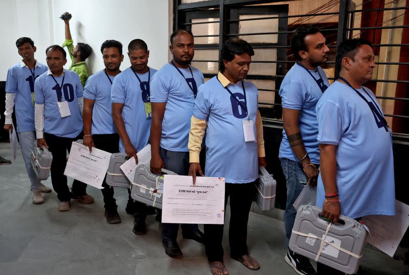 Election staff members carry Electronic Voting Machines before the start of vote counting at a counting centre in Ahmedabad