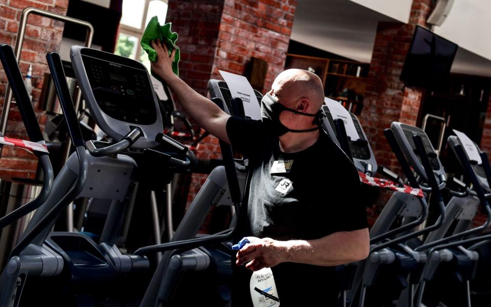 Man wipes down gym equipment - SHUTTERSTOCK