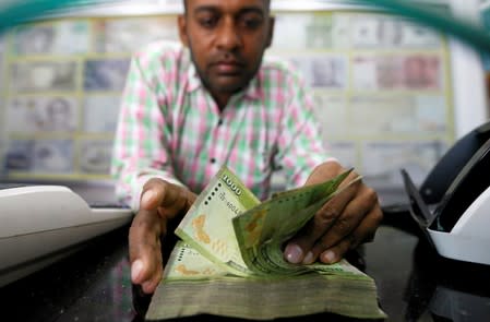 A man counts Sri Lankan rupees notes at a counter of a currency exchange shop in Colombo