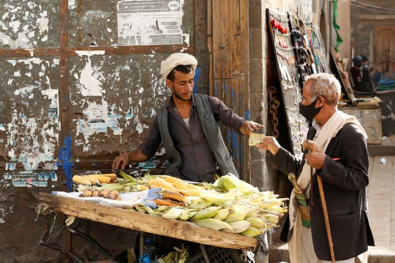 A man wearing a protective mask buys corn in the old quarter of Sanaa