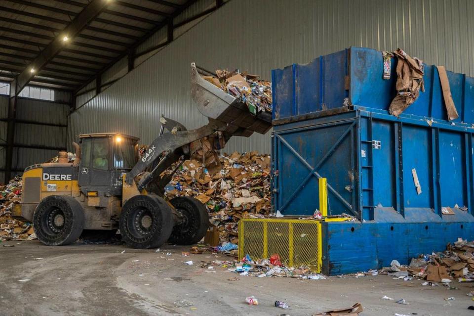 A GFL employee transports a pile of recycling materials on an excavator at the GFL Materials Recovery Facility on Tuesday, March 28, 2023, in Harrisonville, Mo. The recycling materials move through a machine that sorts out the different types of recyclables.